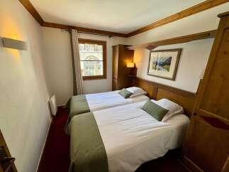 Experience cozy mountain living in this charming hotel room featuring two comfortable twin beds, perfect for solo travelers or friends.
