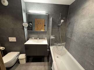 Experience modern luxury in this sleek bathroom featuring a floating vanity with a pristine white sink and a wall-mounted toilet with dual flush.