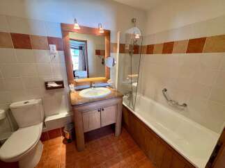 This charming bathroom features a classic white bathtub with a chrome grab bar, perfect for a relaxing soak.
