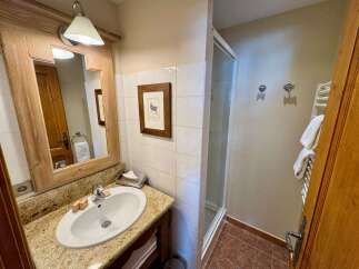 This charming bathroom features a rustic wooden vanity with a granite countertop and a clean white sink.
