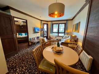 Experience cozy mountain living in this charming apartment, featuring a spacious living area with a dining table perfect for family meals.