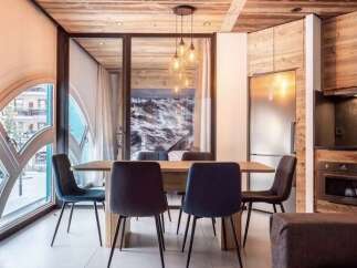Experience modern alpine living in this stunning dining area, featuring a sleek wooden dining table surrounded by plush upholstered chairs.