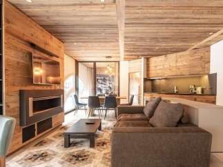 Experience luxurious mountain living in this stunning open-concept living space, featuring a modern fireplace and a sleek entertainment center.
