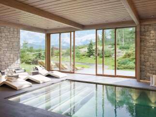 Experience ultimate relaxation in this luxurious indoor pool area, featuring modern lounge chairs and stunning mountain views.