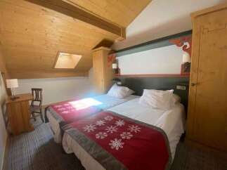 Experience cozy mountain living in this charming hotel room, featuring two comfortable twin beds adorned with festive red throws.