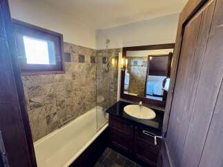 This charming bathroom features a classic white bathtub with a glass shower screen, perfect for relaxing baths or quick showers.