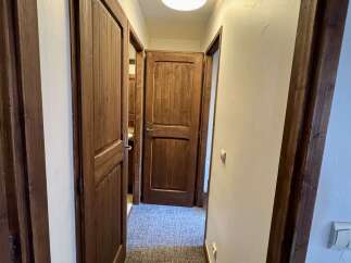 Step into this charming hallway featuring rustic wooden doors and a plush carpeted floor.