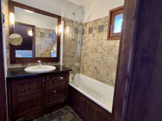 This charming bathroom features a dark wood vanity with a white undermount sink and a granite countertop.