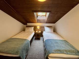 This charming attic bedroom features two cozy twin beds, perfect for accommodating guests or family.