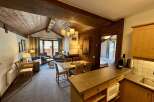 Experience cozy living in this charming mountain retreat, featuring a rustic wood-paneled interior and a vaulted ceiling with exposed beams.