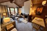 Experience cozy mountain living in this charming living room, featuring a rustic wood-paneled ceiling and a striking stone fireplace.