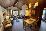 Experience cozy living in this charming mountain retreat, featuring a rustic wood-paneled ceiling and a warm fireplace.