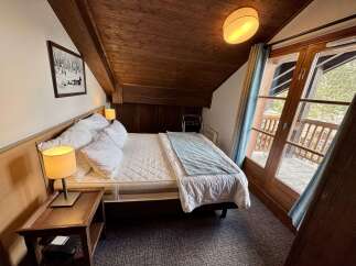 Experience cozy mountain living in this charming bedroom featuring a comfortable bed adorned with plush pillows and a soft throw.