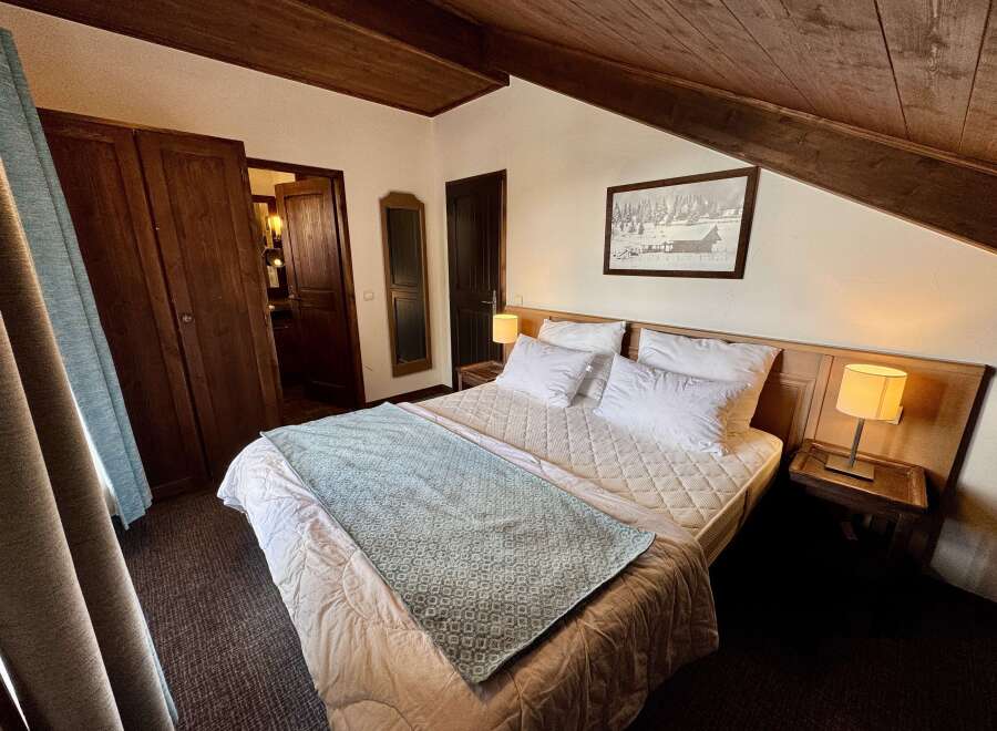 Experience cozy comfort in this charming bedroom featuring a plush bed adorned with crisp white linens and a decorative throw.