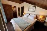 Experience cozy comfort in this charming bedroom featuring a plush bed adorned with crisp white linens and a decorative throw.