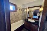 This charming bathroom features a classic white bathtub with a chrome grab bar and a glass shower screen, perfect for relaxing after a long day.