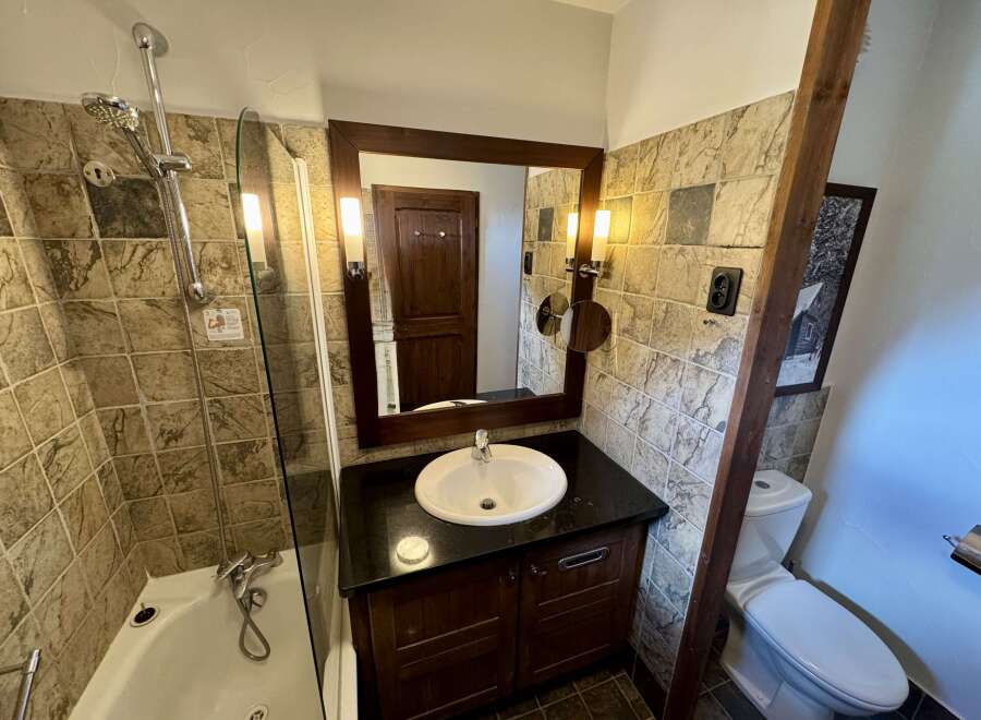 This charming bathroom features a bathtub with a shower, a stylish vanity with a sink, and a toilet.