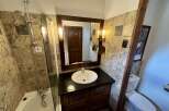 This charming bathroom features a bathtub with a shower, a stylish vanity with a sink, and a toilet.