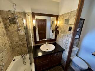 This charming bathroom features a bathtub with a shower, a stylish vanity with a sink, and a toilet.