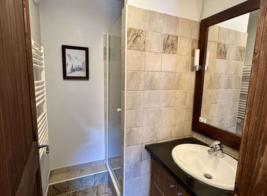 This bathroom features a spacious walk-in shower and a modern vanity with a sleek countertop and ample storage.