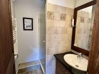 This bathroom features a spacious walk-in shower and a modern vanity with a sleek countertop and ample storage.