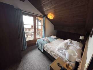 Experience cozy mountain living in this charming hotel room, featuring a comfortable bed adorned with plush pillows and a serene teal throw.