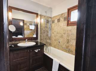 Experience rustic charm in this bathroom featuring a deep soaking tub with a glass enclosure and a stylish vanity with a vessel sink.