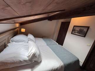 Experience cozy comfort in this charming attic bedroom, featuring two inviting beds dressed in crisp white linens.