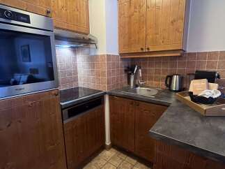This charming kitchen features warm wooden cabinetry and a sleek stainless steel oven.
