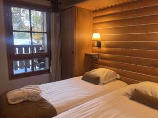 Experience cozy mountain living in this charming hotel room, featuring two comfortable beds and a plush bathrobe laid out for your relaxation.
