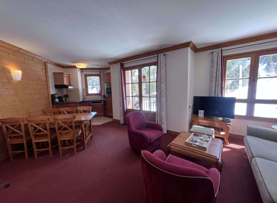 Experience cozy mountain living in this charming apartment, featuring a spacious dining area with a large wooden table and chairs, perfect for family meals.