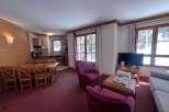 Experience cozy mountain living in this charming apartment, featuring a spacious dining area with a large wooden table and chairs, perfect for family meals.
