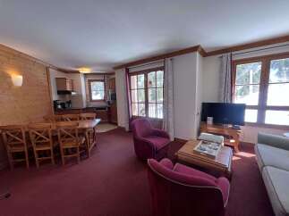 Experience cozy mountain living in this charming apartment, featuring a spacious dining area with a large wooden table and chairs, perfect for family meals.