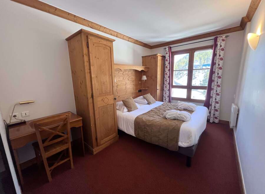 Experience cozy mountain living in this charming hotel room, featuring a comfortable bed with plush linens and a rustic wooden headboard.
