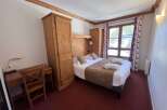 Experience cozy mountain living in this charming hotel room, featuring a comfortable bed with plush linens and a rustic wooden headboard.