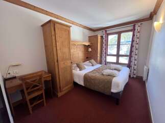 Experience cozy mountain living in this charming hotel room, featuring a comfortable bed with plush linens and a rustic wooden headboard.