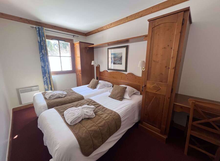 Experience comfort and style in this charming hotel room, featuring two cozy twin beds adorned with plush white linens and warm brown throws.