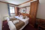 Experience comfort and style in this charming hotel room, featuring two cozy twin beds adorned with plush white linens and warm brown throws.
