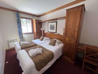 Experience comfort and style in this charming hotel room, featuring two cozy twin beds adorned with plush white linens and warm brown throws.
