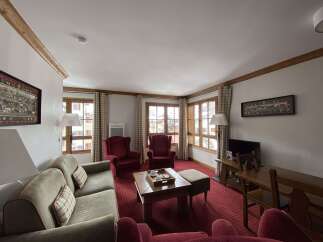 Experience cozy living in this charming mountain retreat, featuring a spacious living area with plush seating and a traditional wooden coffee table.