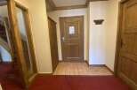 Step into a warm and inviting entryway featuring rich wooden doors and trim, complemented by a classic red carpet.