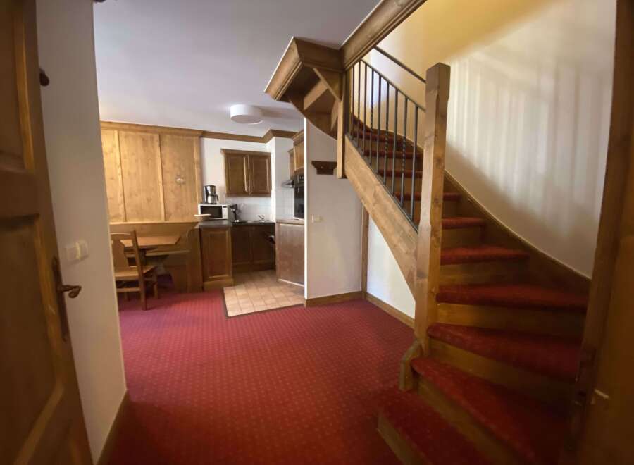 Discover this charming interior featuring a cozy kitchen area with wooden cabinets and a dining nook, perfect for intimate meals.