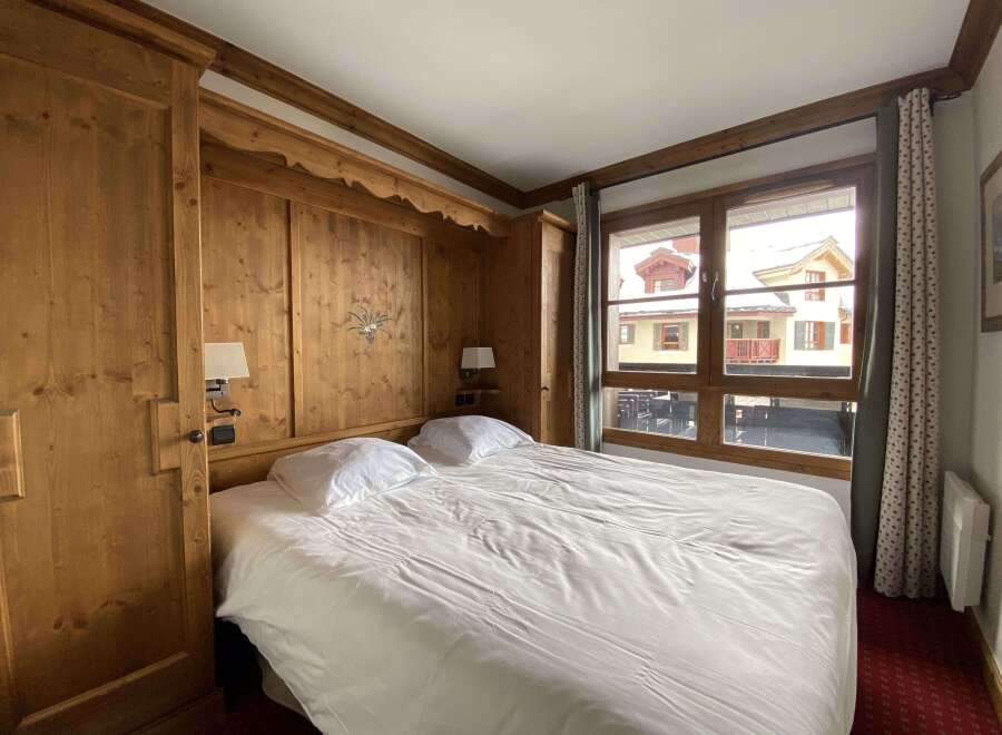 Experience cozy mountain living in this charming bedroom featuring warm wood paneling and a comfortable queen-sized bed.