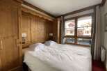 Experience cozy mountain living in this charming bedroom featuring warm wood paneling and a comfortable queen-sized bed.