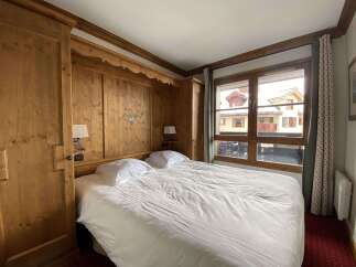 Experience cozy mountain living in this charming bedroom featuring warm wood paneling and a comfortable queen-sized bed.