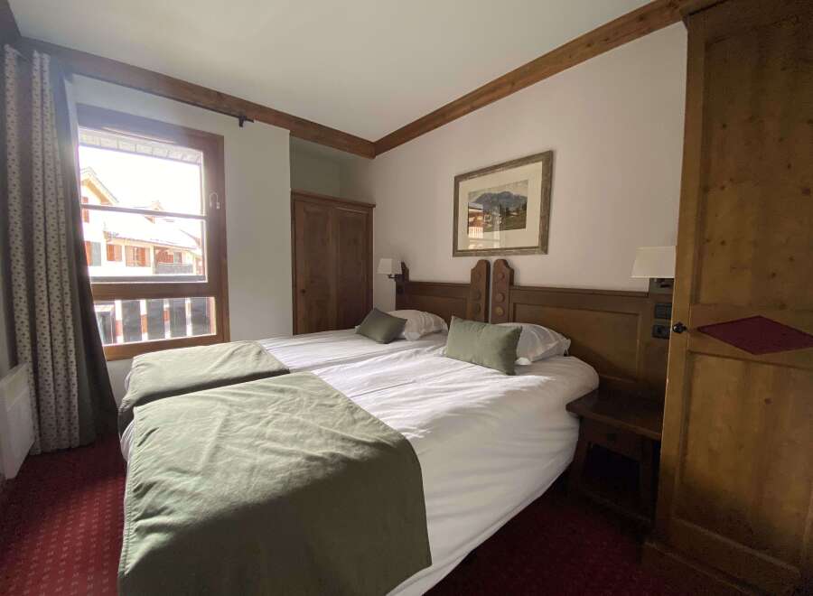 Experience cozy mountain living in this charming hotel room featuring two comfortable beds adorned with plush green throws.