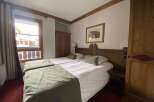 Experience cozy mountain living in this charming hotel room featuring two comfortable beds adorned with plush green throws.