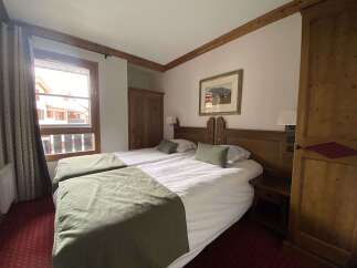 Experience cozy mountain living in this charming hotel room featuring two comfortable beds adorned with plush green throws.
