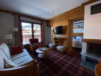 Experience cozy living in this charming mountain retreat, featuring a spacious living area with a plush sofa and a comfortable armchair perfect for relaxing.