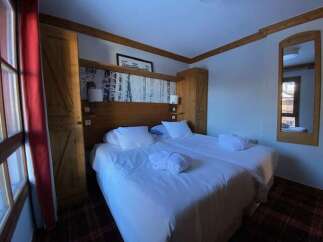 Experience ultimate comfort in this charming hotel room, featuring two plush beds adorned with crisp white linens and fluffy bathrobes.